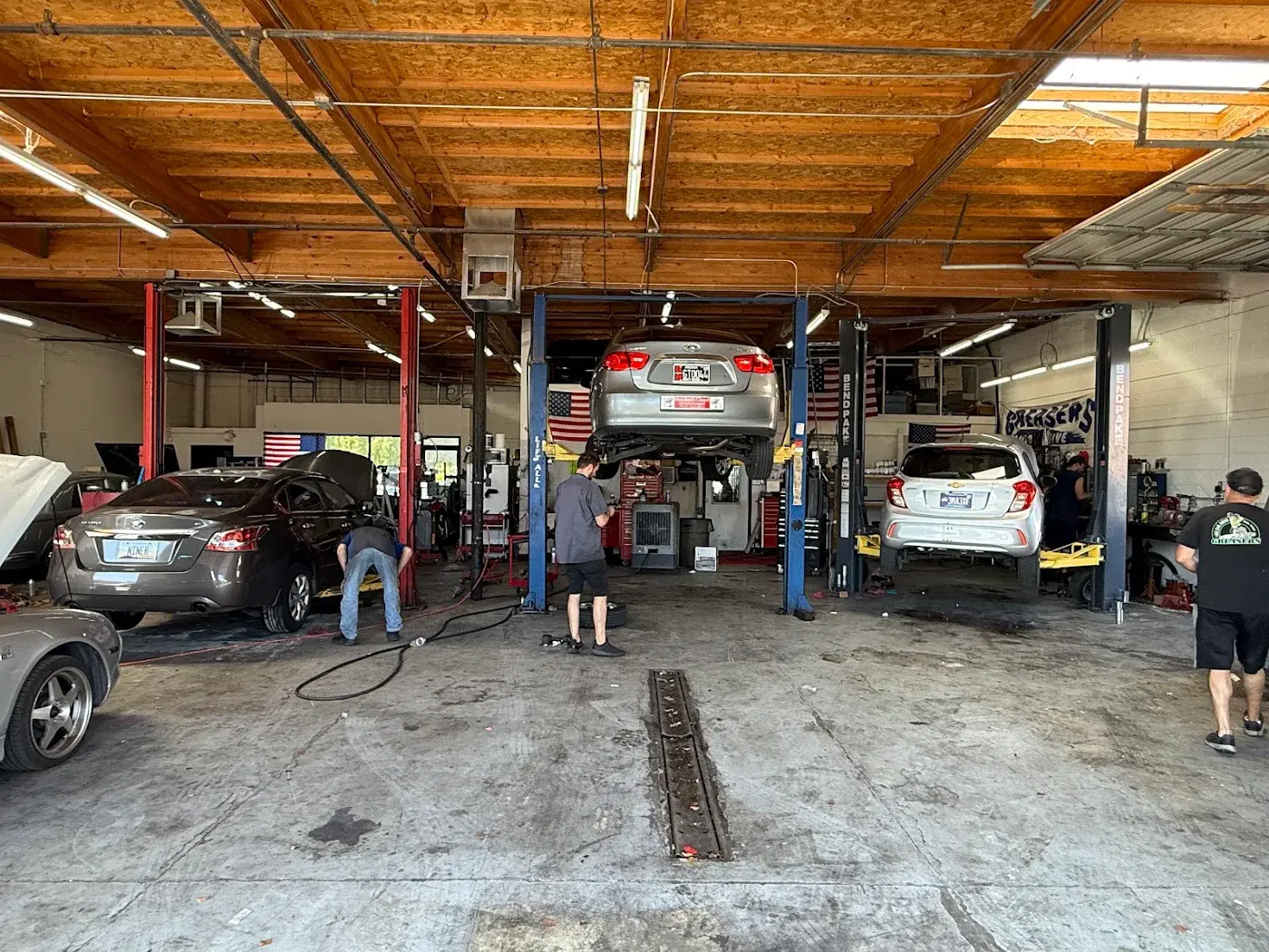 Mechanics working on cars inside Greasers Automotive